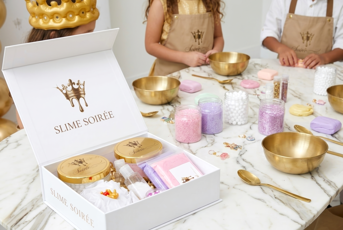 Children in gold crowns stretching slime at a marble party table
